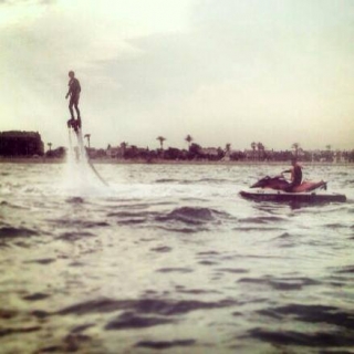  boy practicing flyboarding while another man drives a jet ski 